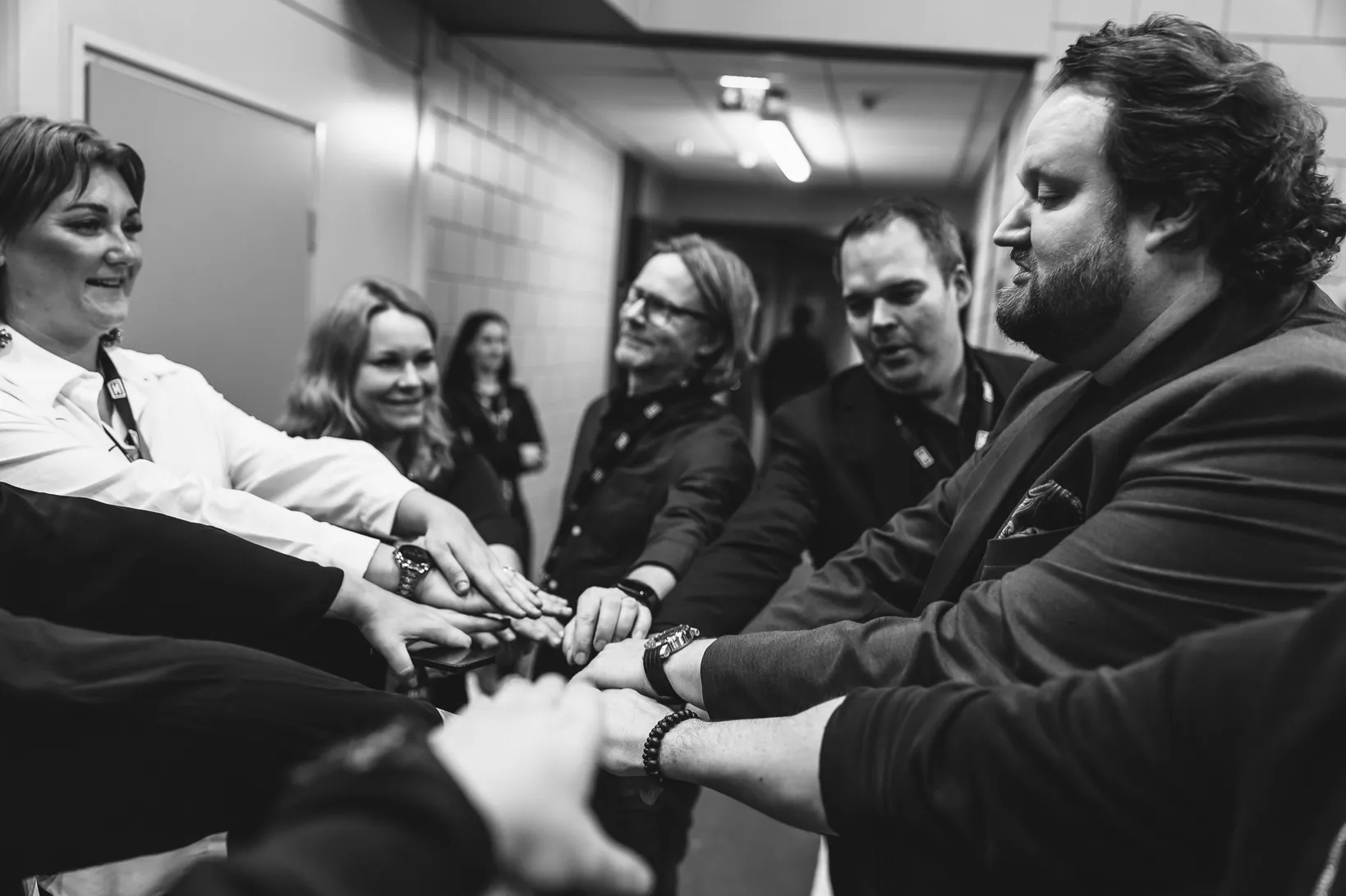 Sami Hedberg ja tiimi yhdistävät kätensä ennen esitystä, mustavalkoinen kuva